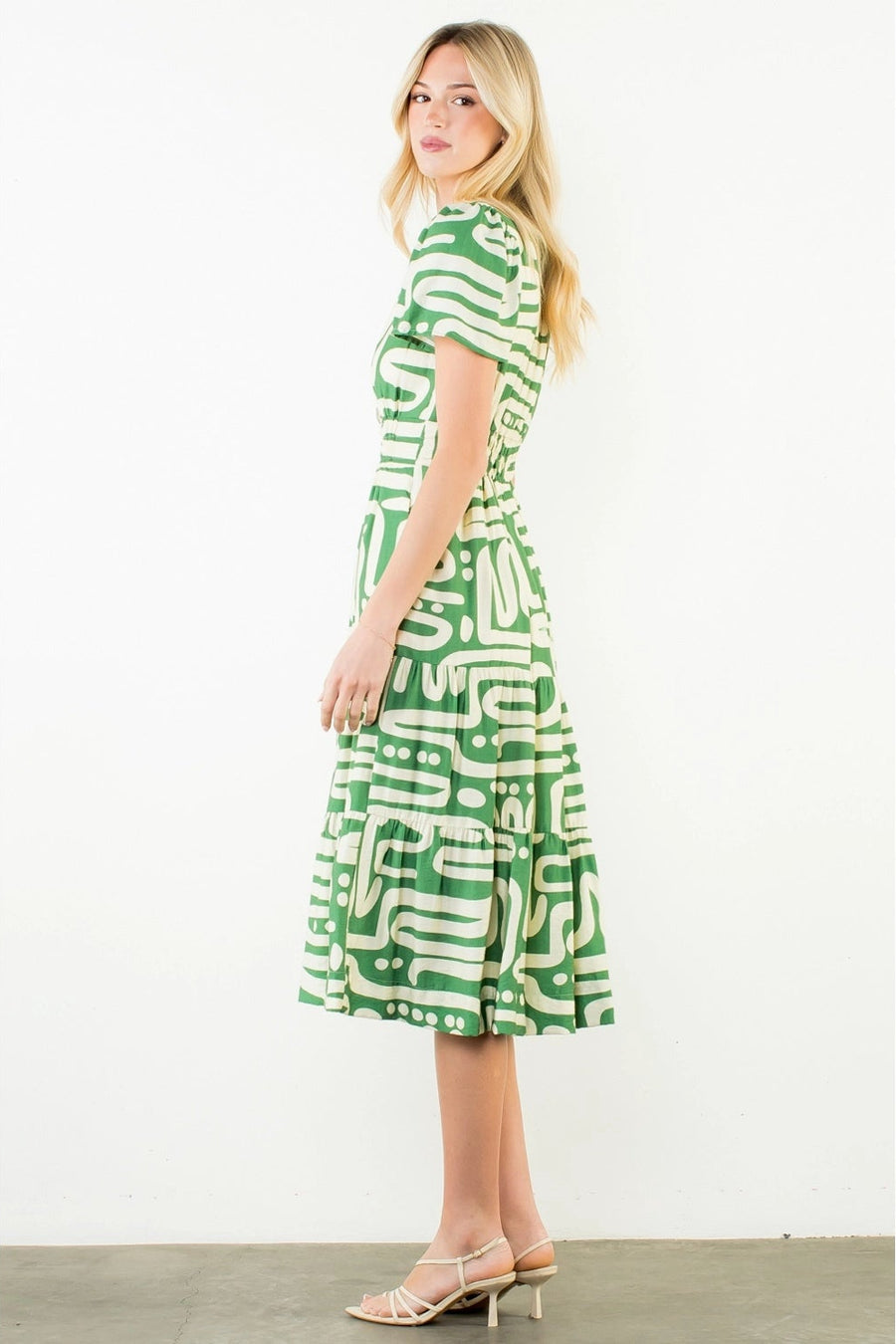 Woman wearing a green and white patterned dress on a white background