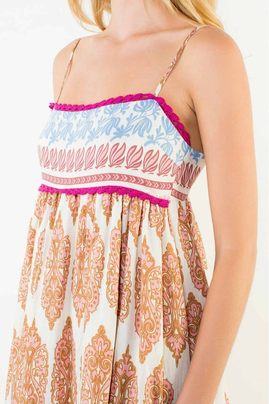 Woman wearing a patterned dress with pink trim on a white background