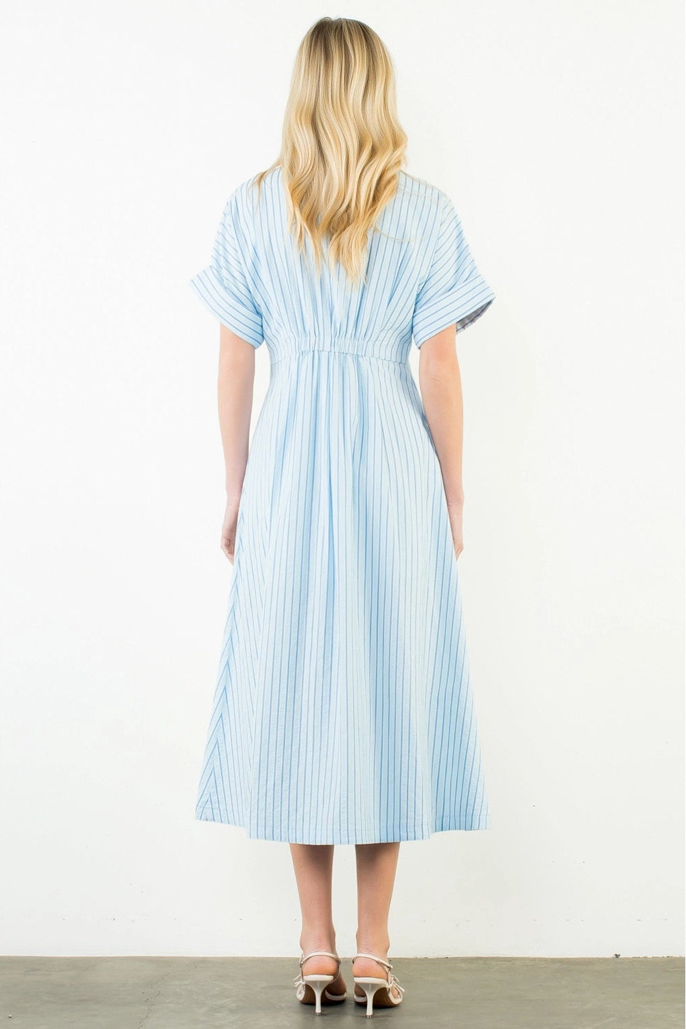Woman wearing a blue and white striped dress on a white background