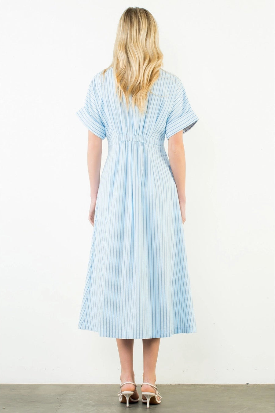 Woman wearing a blue and white striped dress on a white background