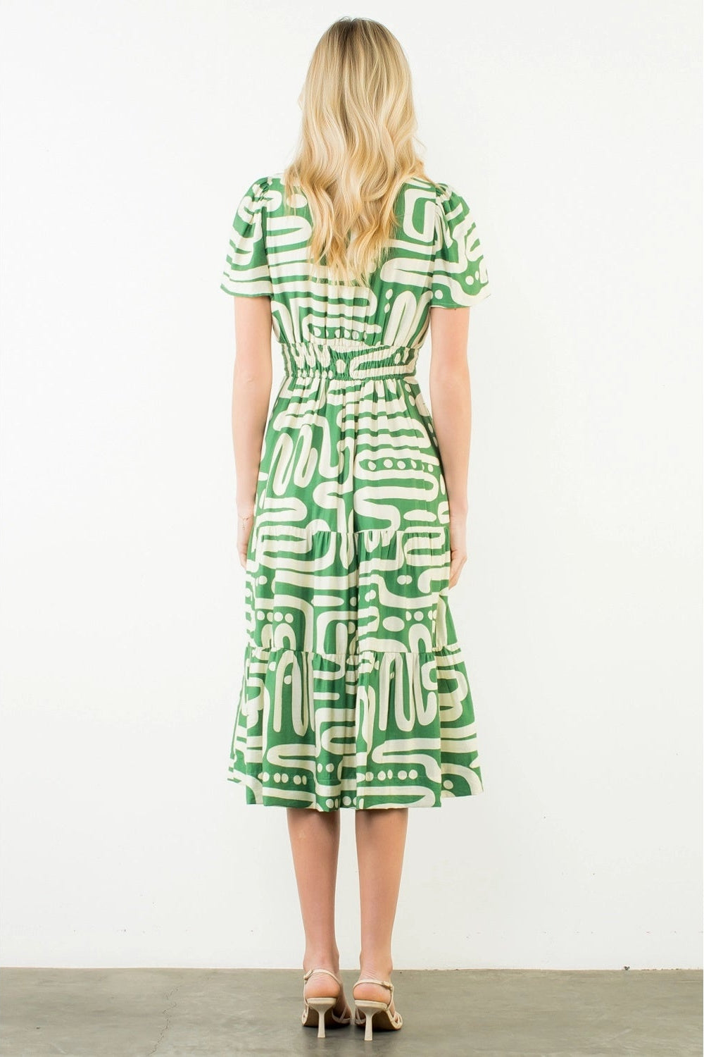 Woman wearing a green and white patterned dress on a white background