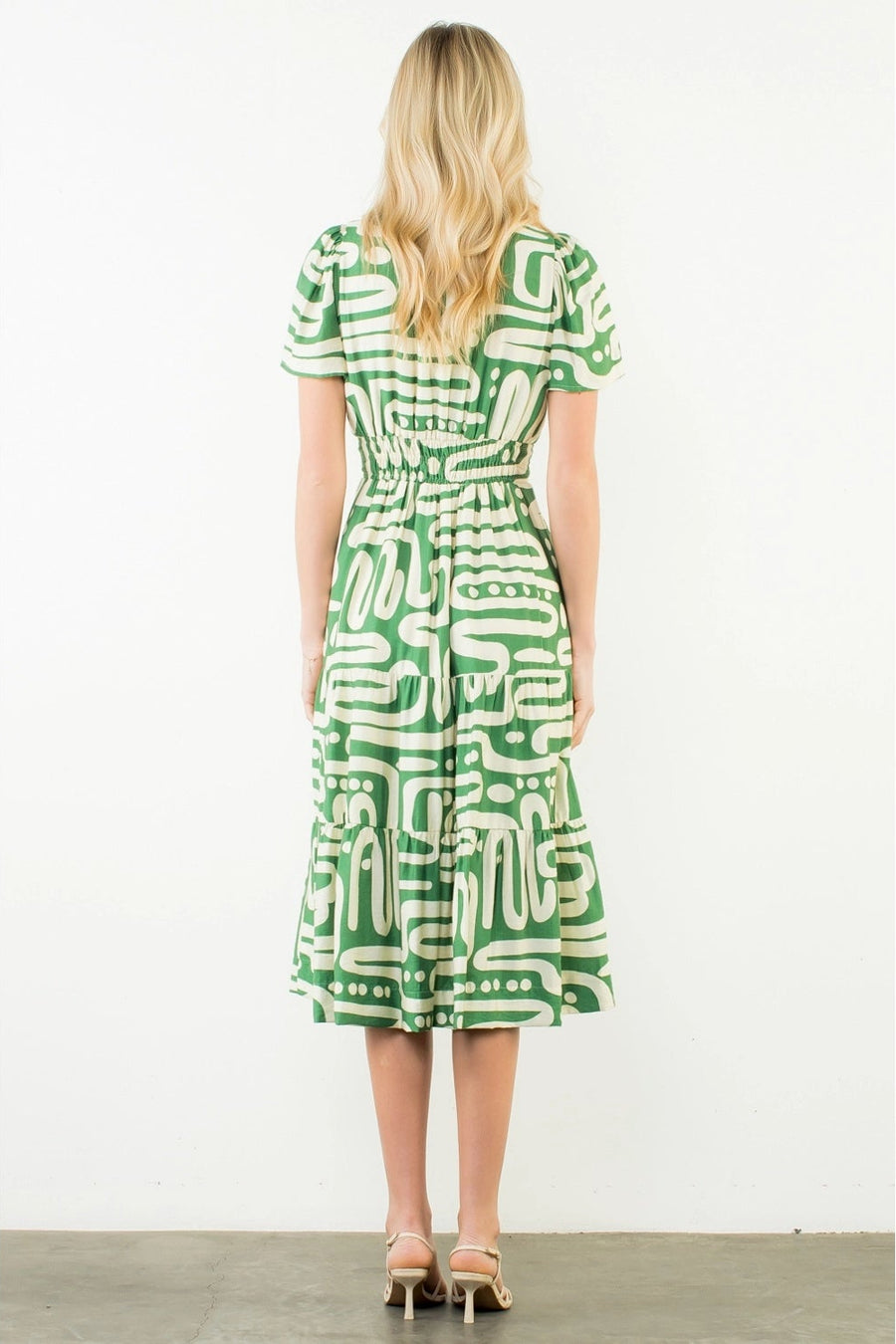 Woman wearing a green and white patterned dress on a white background