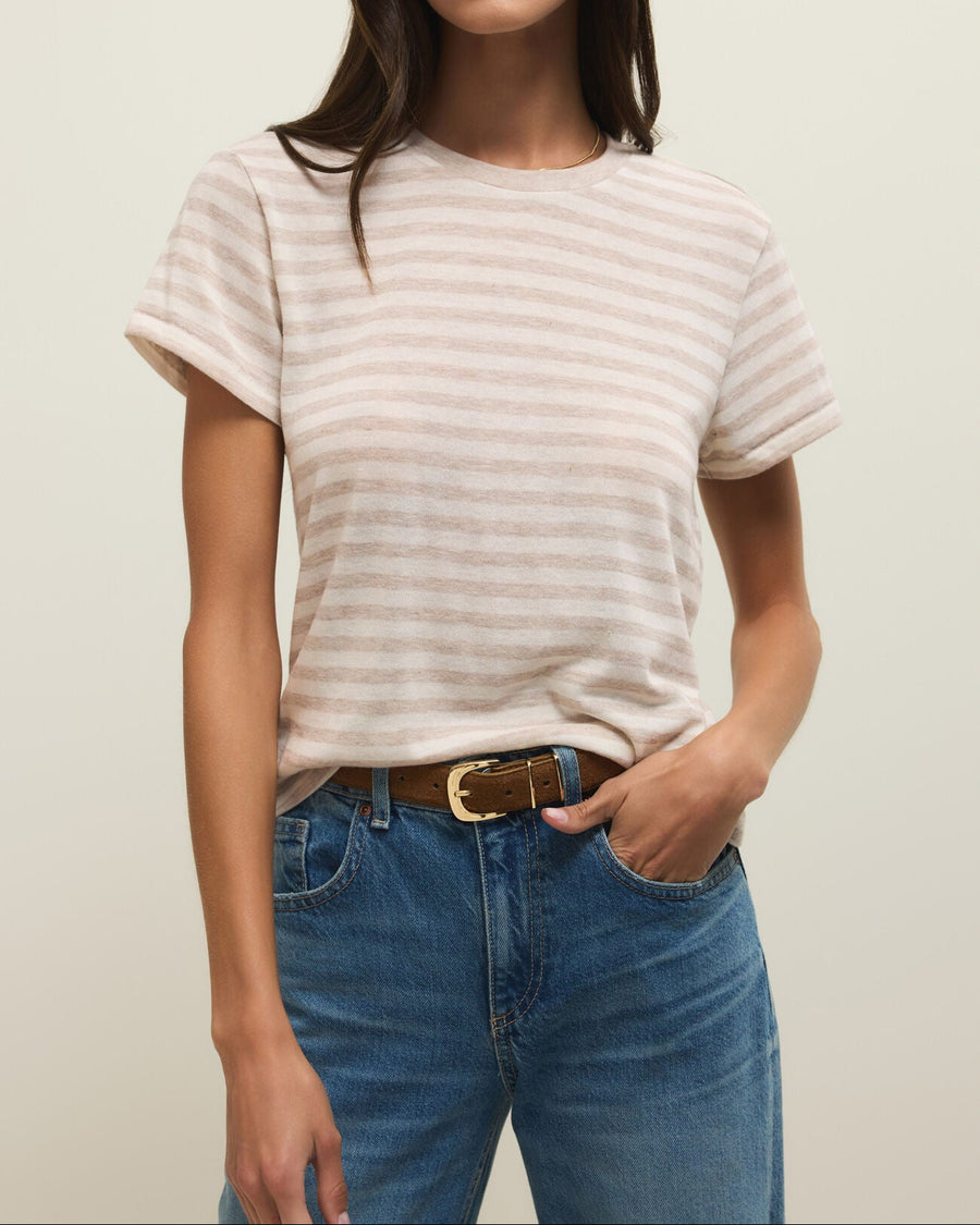 Woman wearing a striped shirt and blue jeans against a plain background