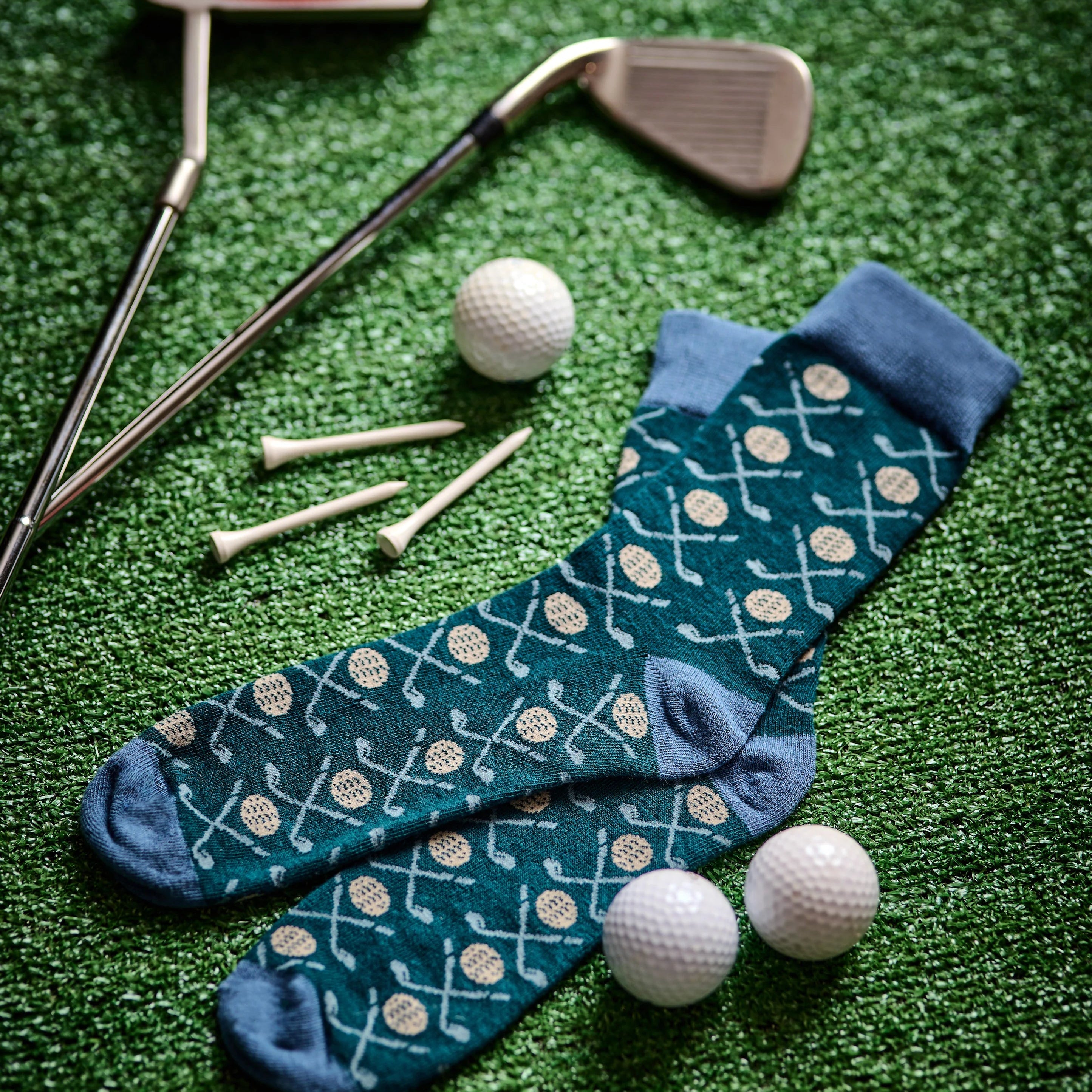 Golf-themed socks with golf clubs and balls on a green surface