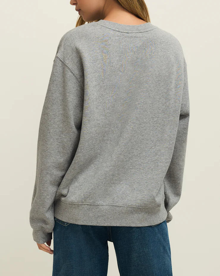 Person wearing a gray sweatshirt and blue jeans on a plain background
