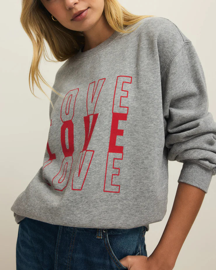 Woman wearing a gray sweatshirt with red 'LOVE' text on a plain background