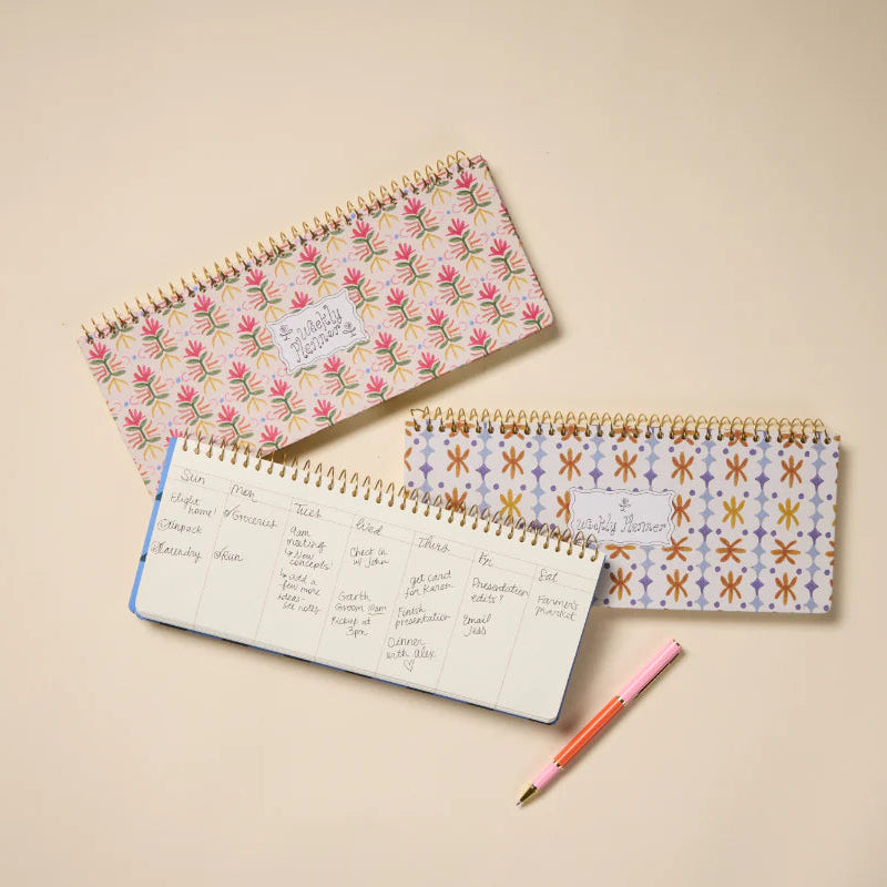 Three spiral-bound notebooks with floral and geometric patterns on a beige background