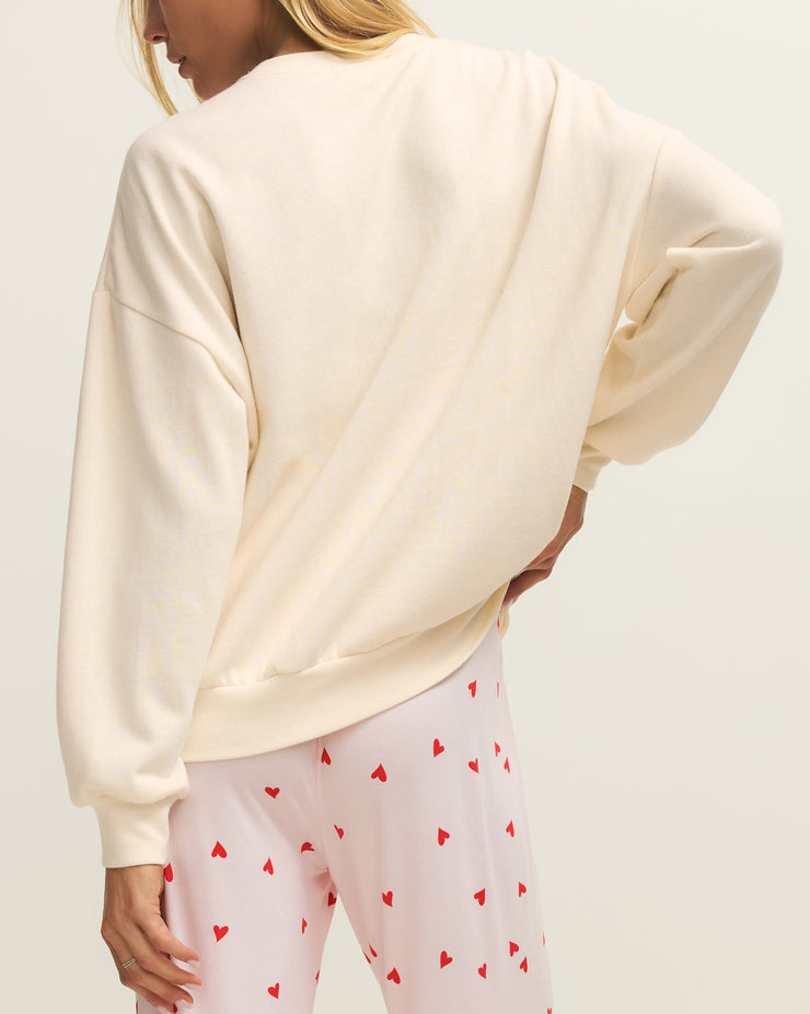 Person wearing a cream oversized sweatshirt and light pink leggings with red heart patterns on a white background