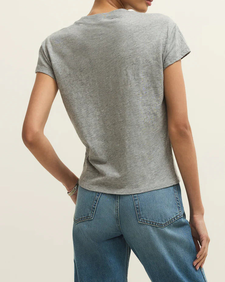 Woman wearing a gray t-shirt and blue jeans on a beige background