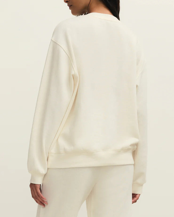 Person wearing a cream-colored sweater and pants on a plain background