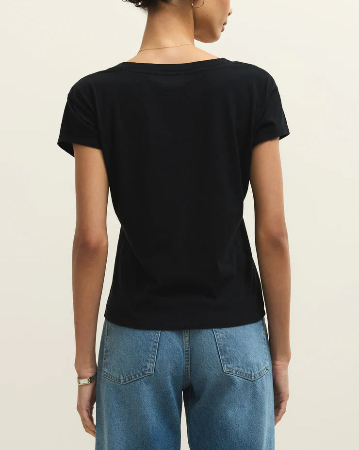 Person wearing a black t-shirt and blue jeans on a beige background