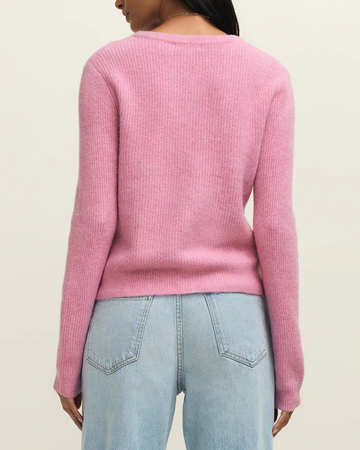 Person wearing a pink sweater and light blue jeans on a beige background