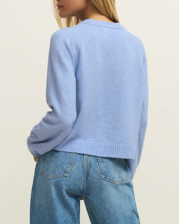 Person wearing a light blue sweater and jeans on a plain background