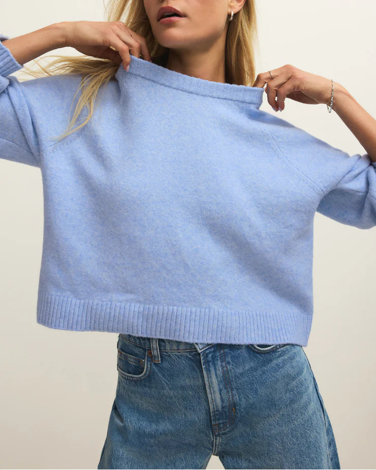 Woman wearing a light blue sweater and jeans against a plain background