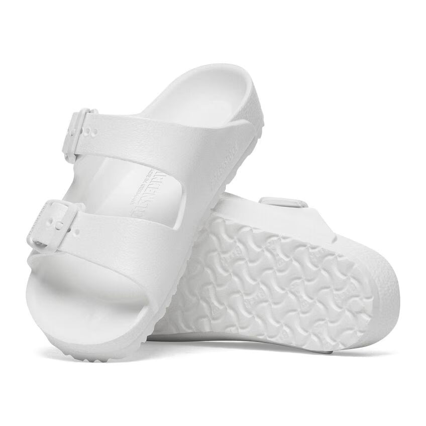 A pair of white Birkenstock Kids EVA Arizona sandals with two straps and metal tongue buckles on a textured white sole.