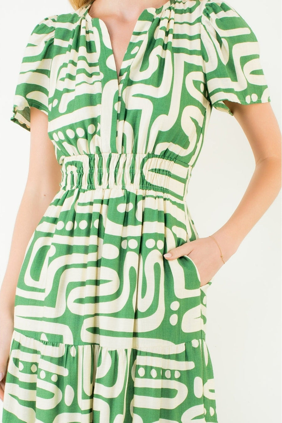 Green and white patterned dress worn by a person on a white background