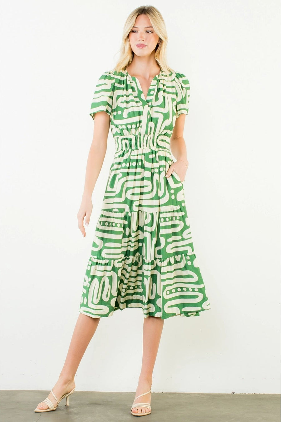 Woman wearing a green and white patterned dress on a white background