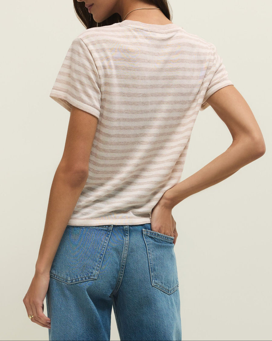 Woman wearing a striped t-shirt and blue jeans against a plain background
