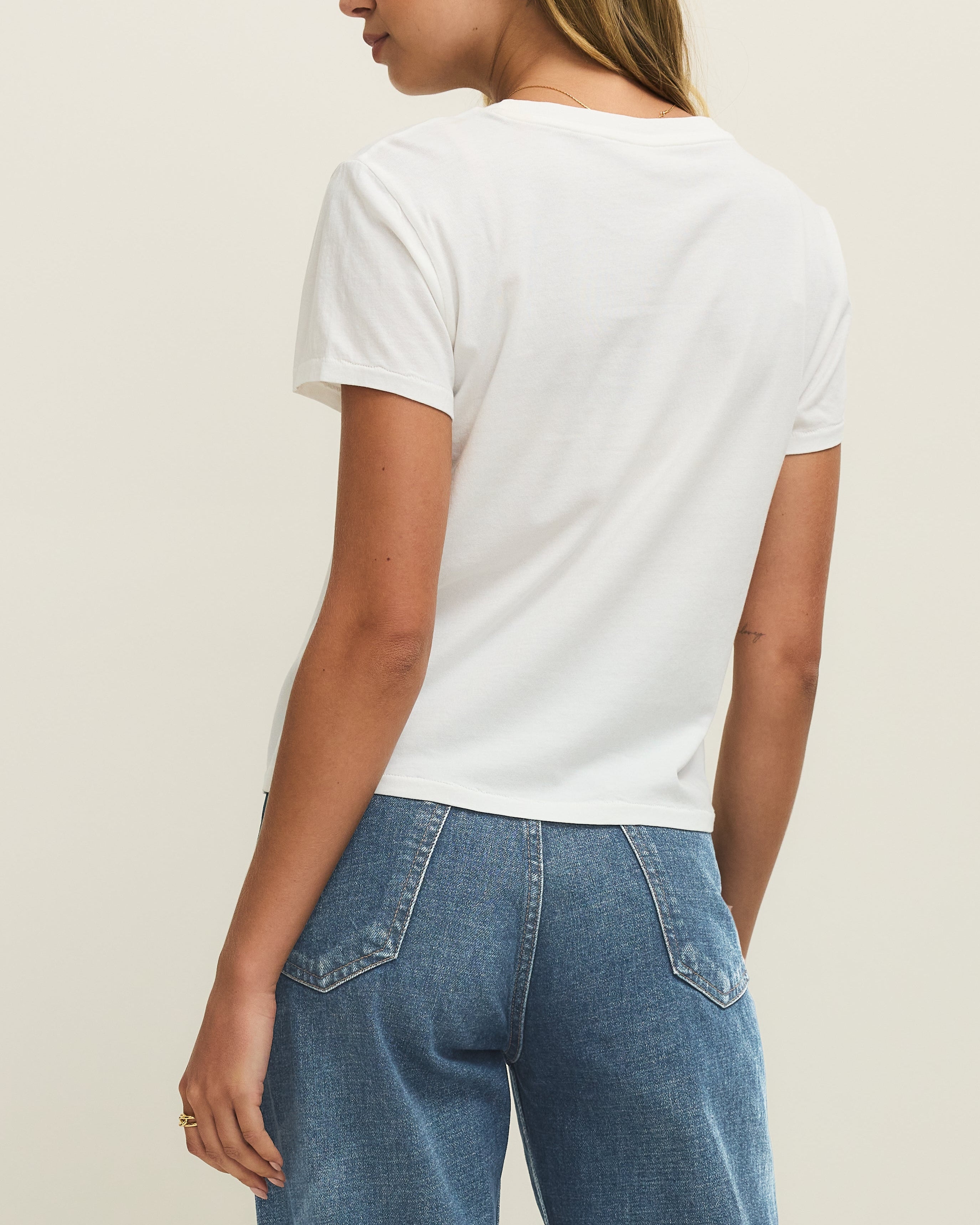 Person wearing a white t-shirt and blue jeans on a plain background