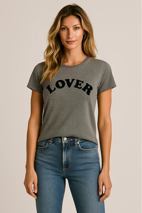 Woman wearing a gray t-shirt with 'LOVER' text and blue jeans on a beige background