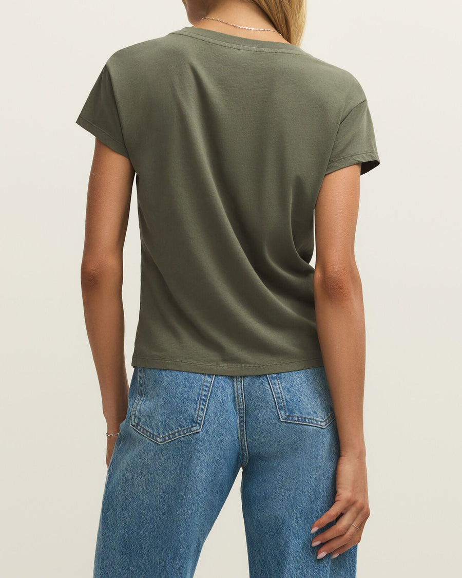 Person wearing an olive green t-shirt and blue jeans on a plain background